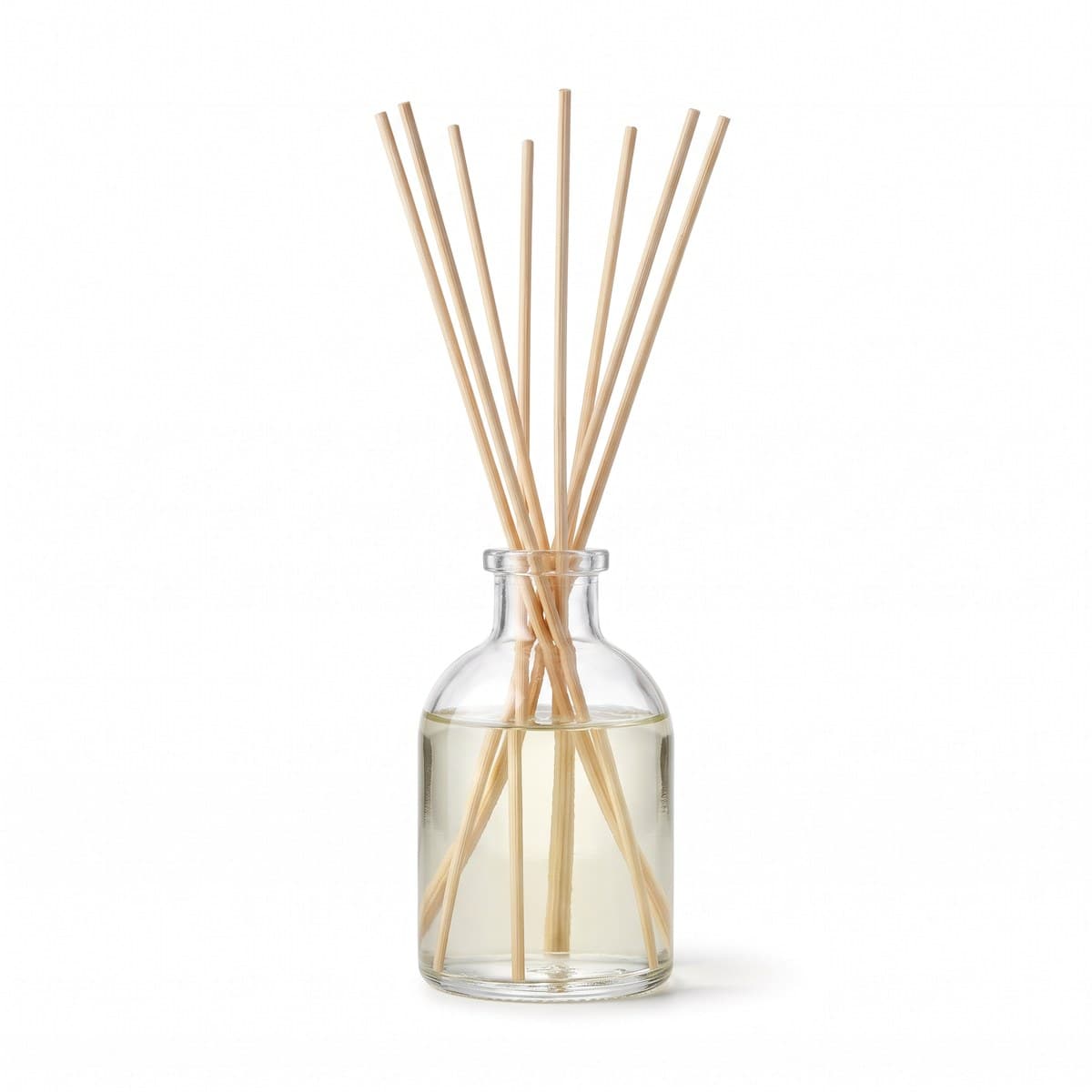 A clear glass bottle of scented oil with eight rattan reeds standing in the neck